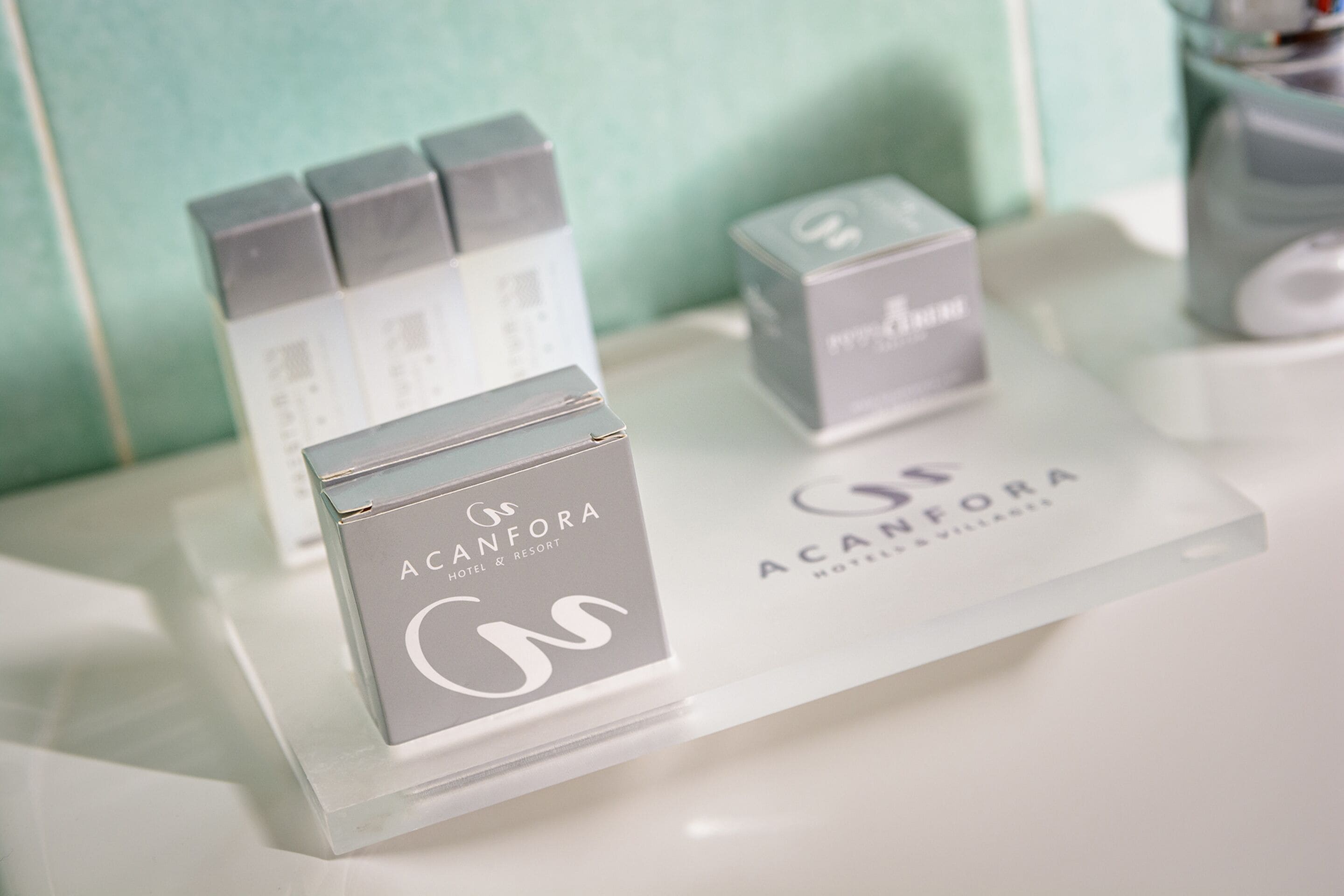 Une sélection de produits de la marque Acanfora Hotel & Resort est exposée sur une étagère transparente.