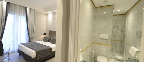 Una habitación de hotel moderna con una cama grande, un escritorio y un baño separado con ducha e inodoro.
