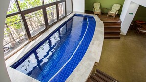 An indoor swimming pool with a view of a cityscape through large windows. - Estanplaza Paulista (São Paulo)