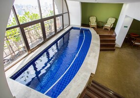 An indoor swimming pool with a view of a cityscape through large windows.