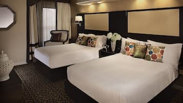 Habitación de hotel con dos camas, un espejo grande, una mesita de noche con lámpara y un jarrón decorativo.