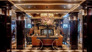 A lobby with a checkered floor, a stone fireplace, and a large floral arrangement. - The Inn At Fox Hollow Hotel (Woodbury)