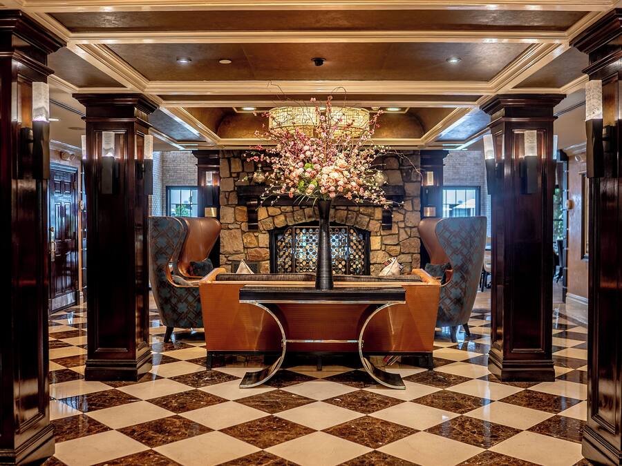 A lobby with a checkered floor, a stone fireplace, and a large floral arrangement.
