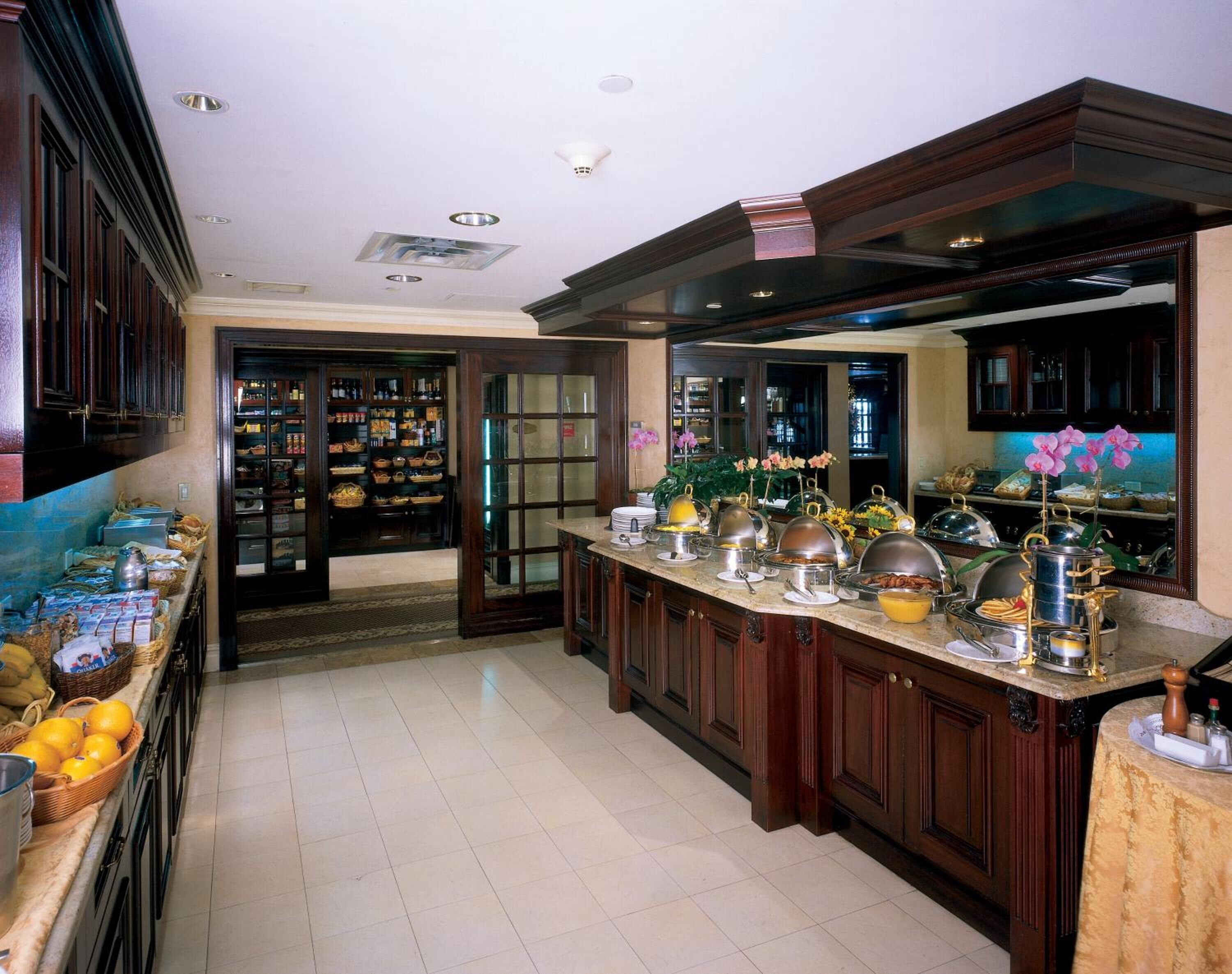A spacious kitchen with dark wood cabinets, a marble countertop, and a variety of kitchen appliances and utensils.