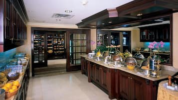 A spacious kitchen with dark wood cabinets, a marble countertop, and a variety of kitchen appliances and utensils.