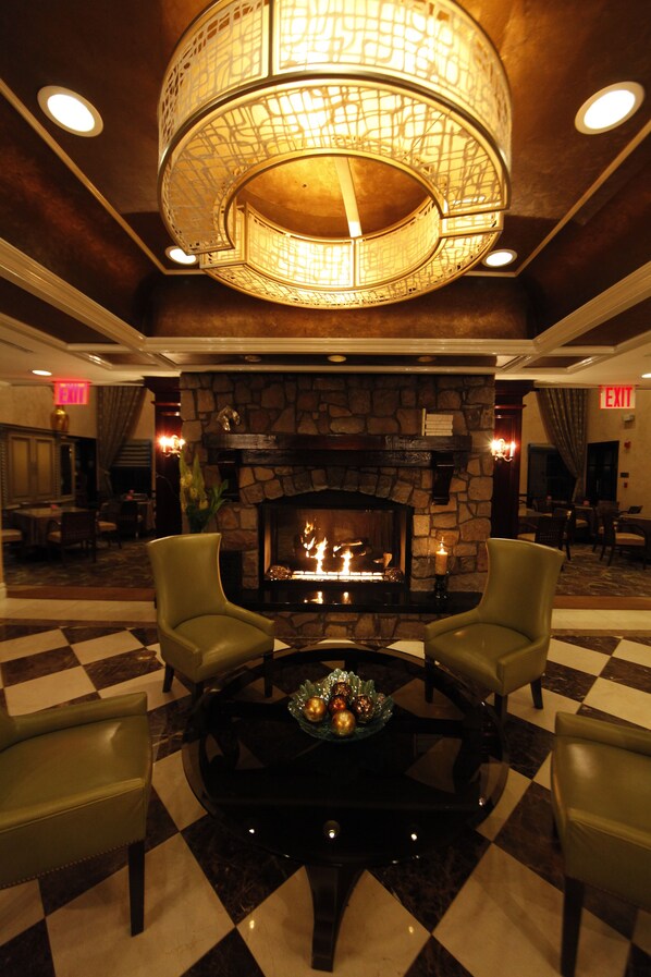 A lobby with a stone fireplace, a checkered floor, and a central table with chairs. - The Inn At Fox Hollow Hotel (Woodbury)
