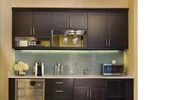 Una cocina con armarios oscuros, un microondas de acero inoxidable, una cafetera y un salpicadero de vidrio.
