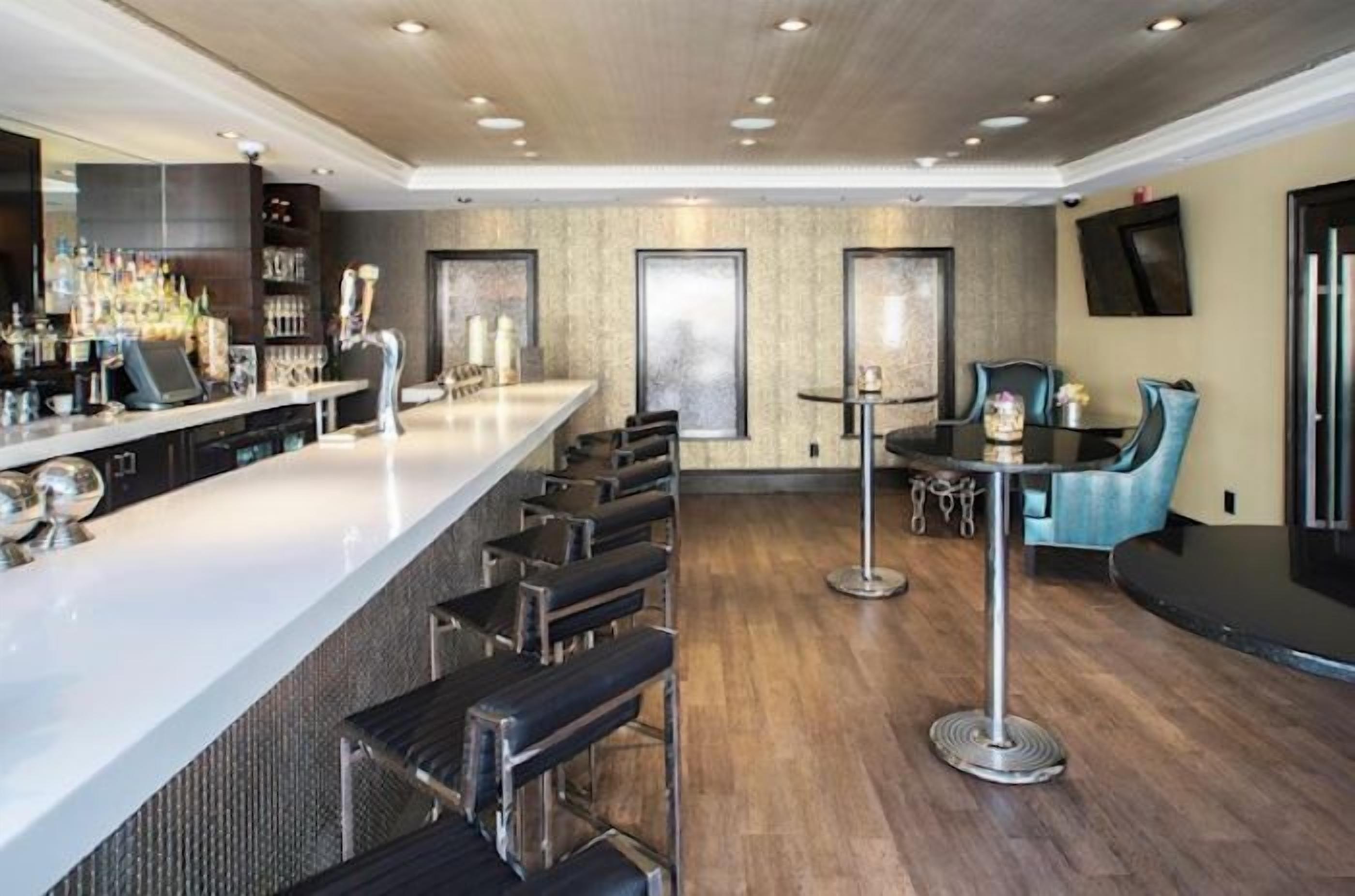 Un espace bar moderne avec un long comptoir, des tabourets de bar et une table ronde avec des chaises.