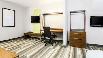 A hotel room with a desk, chair, flat-screen TV, and a bed.
