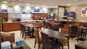 A modern cafe with wooden tables and chairs, a bakery counter, and a breakfast bar. - Holiday Inn Express Philadelphia NE - Langhorne by IHG (Langhorne)