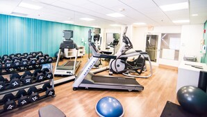 A gym with treadmills, elliptical machines, and a rack of dumbbells.