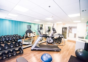 A gym with treadmills, elliptical machines, and a rack of dumbbells.