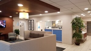 A reception area with a counter, seating, and a TV screen.
