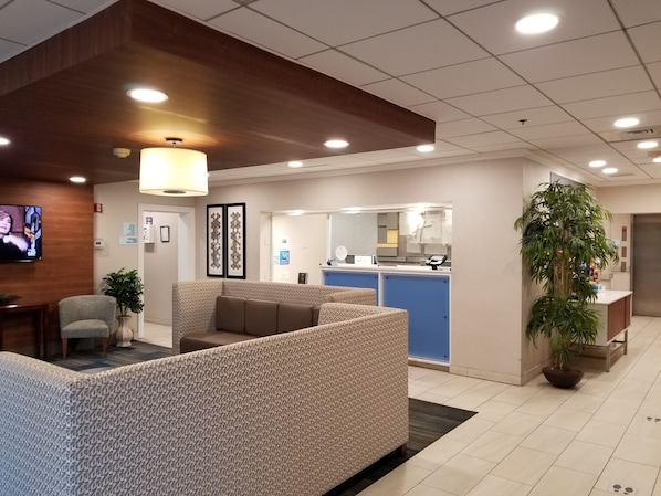 A reception area with a counter, seating, and a TV screen.