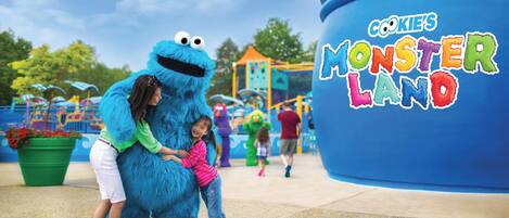 A mascot interacting with children at a theme park entrance.