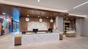 Un espace d’accueil moderne avec un comptoir de réception blanc, deux écrans et une enseigne indiquant « Boutique des suites ».