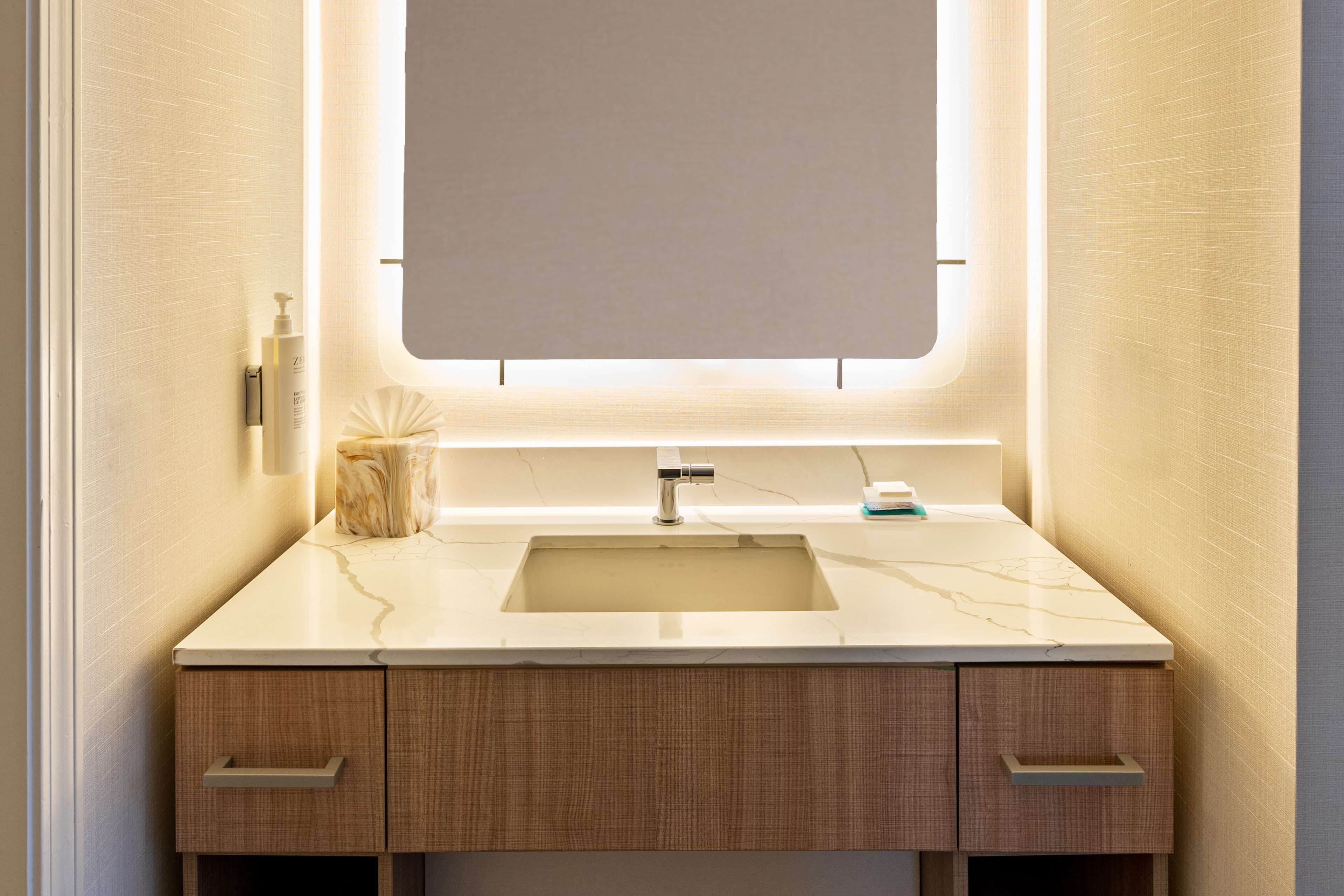Une salle de bain avec un lavabo en marbre, des meubles en bois et un grand miroir.