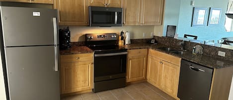 A kitchen with wooden cabinets, a stainless steel refrigerator, a microwave, an oven, and a dishwasher.