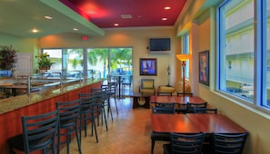 A restaurant with a bar area, outdoor seating, and a view of the greenery outside. - Sunset Vistas Two Bedroom Beachfront Suites (Treasure Island)