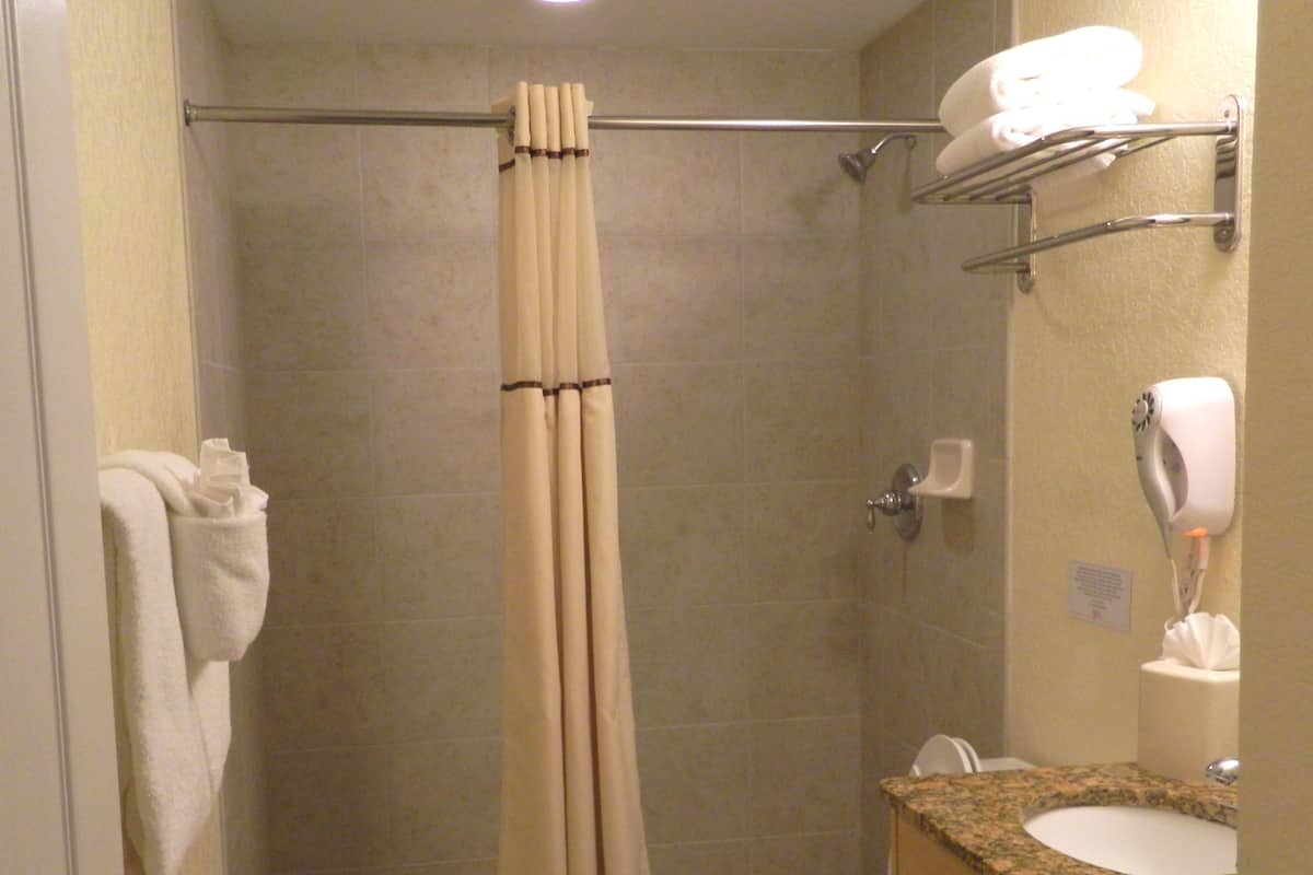 A bathroom with a shower curtain, a toilet, a sink, and a towel rack.