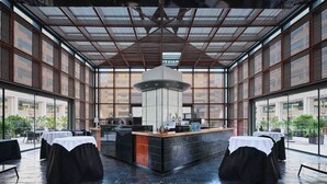 Un interior moderno con una zona de bar central, ventanas amplias y un techo alto.