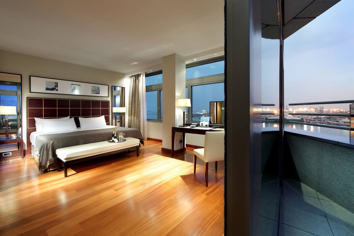 Een moderne hotelkamer met een groot bed, een bureau en uitzicht op een stadsbeeld.