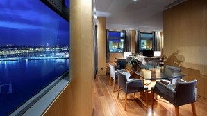 Un moderno comedor con mesa y sillas de vidrio, vista a un paisaje urbano nocturno y un ventanal grande.