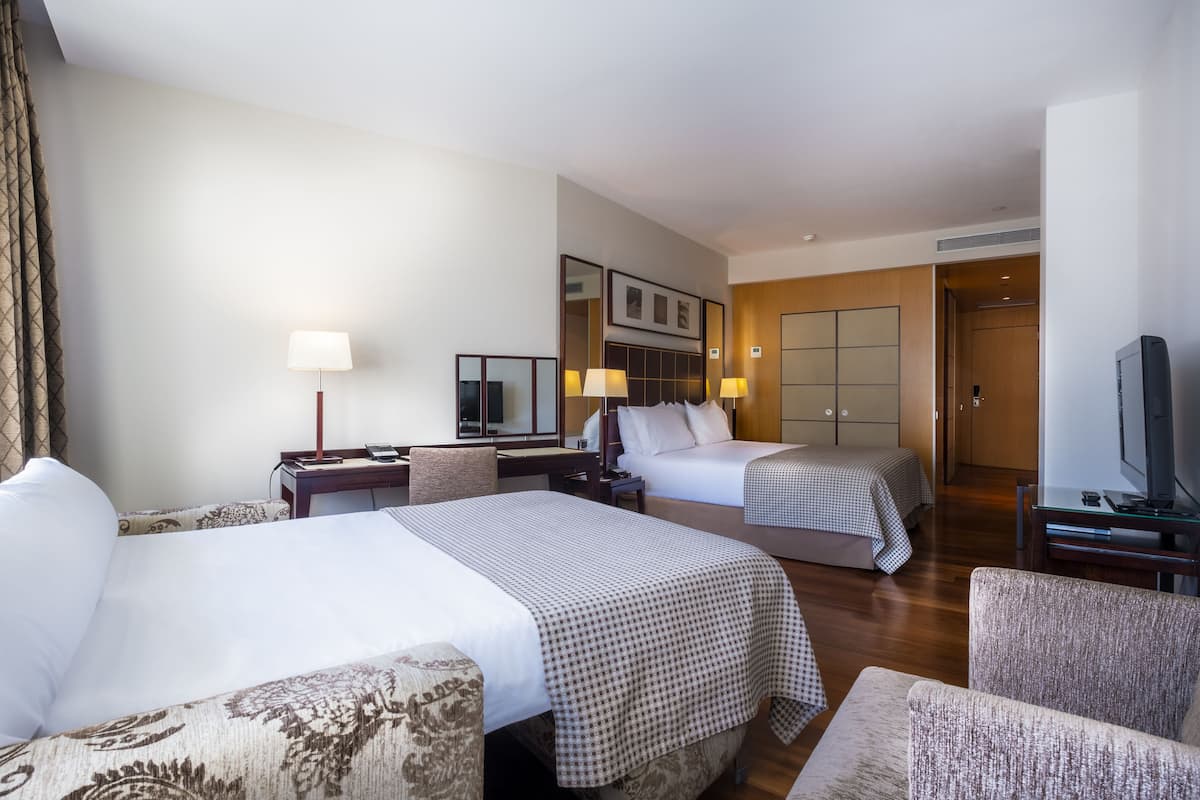 Een hotelkamer met twee bedden, een bureau, een stoel, een televisie en een kledingkast.