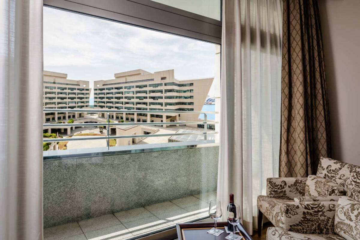Een hotelkamer met een groot raam dat uitzicht biedt op een modern gebouwcomplex.
