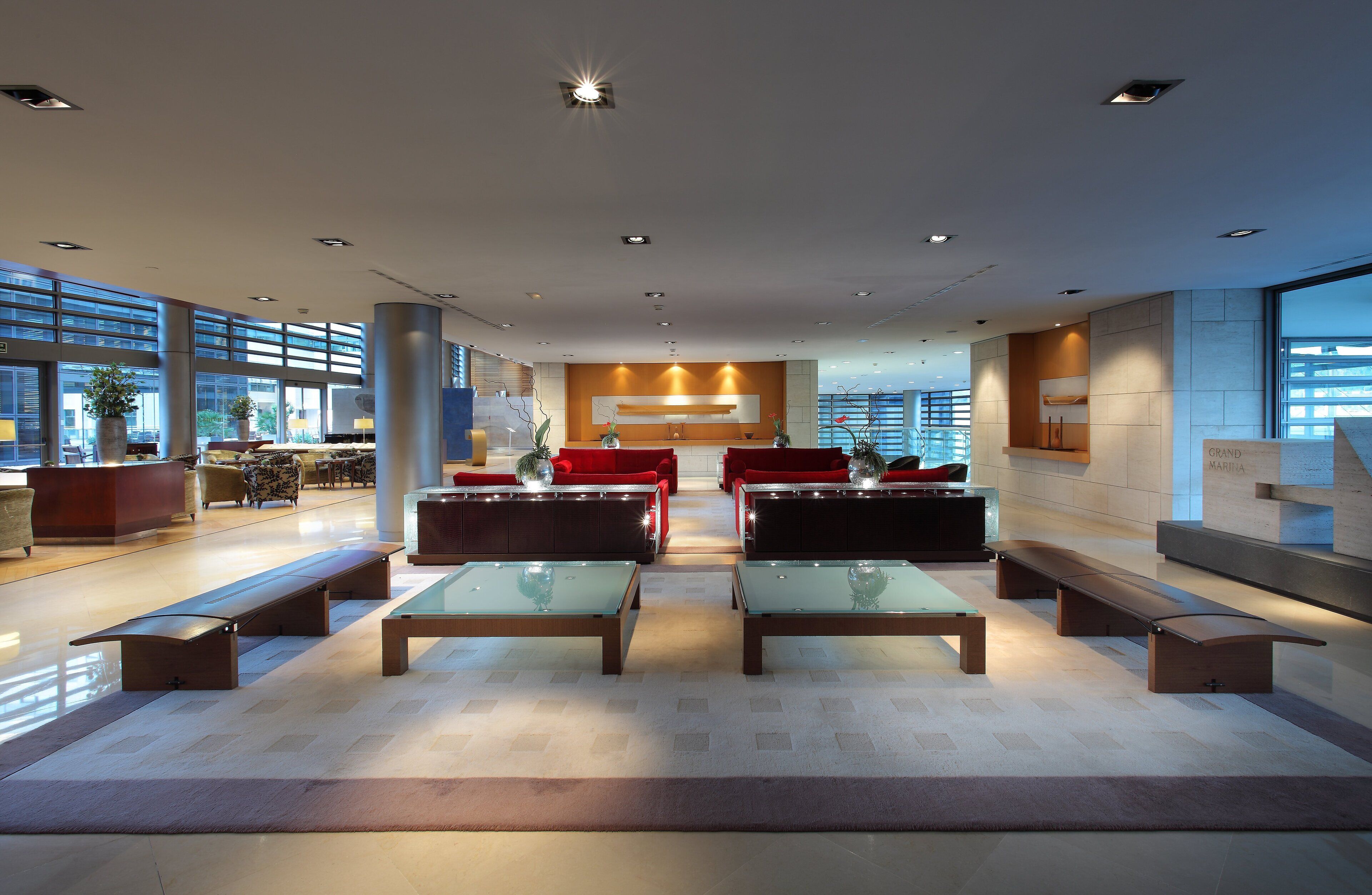 A spacious lobby with modern seating, large windows, and a central light fixture.