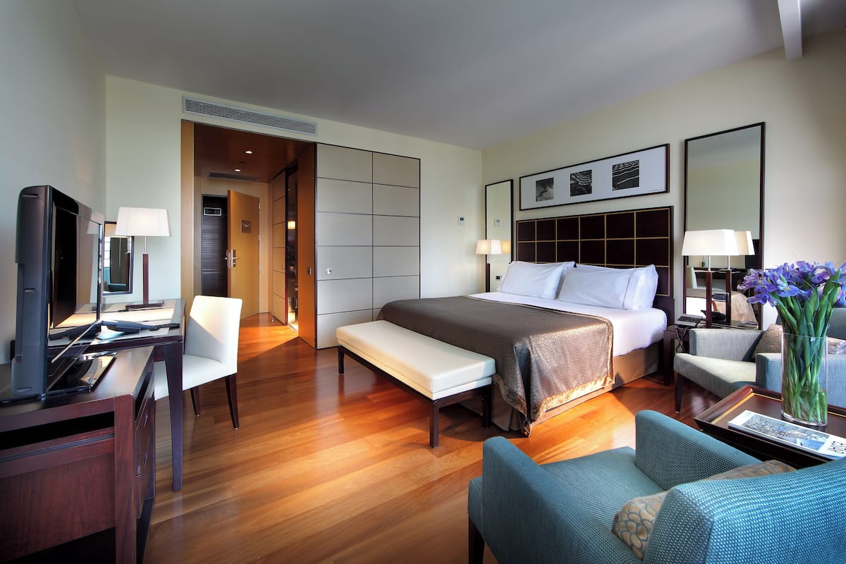 Een hotelkamer met een bed, een bureau met een computer, een stoel, een bankje en een bank.