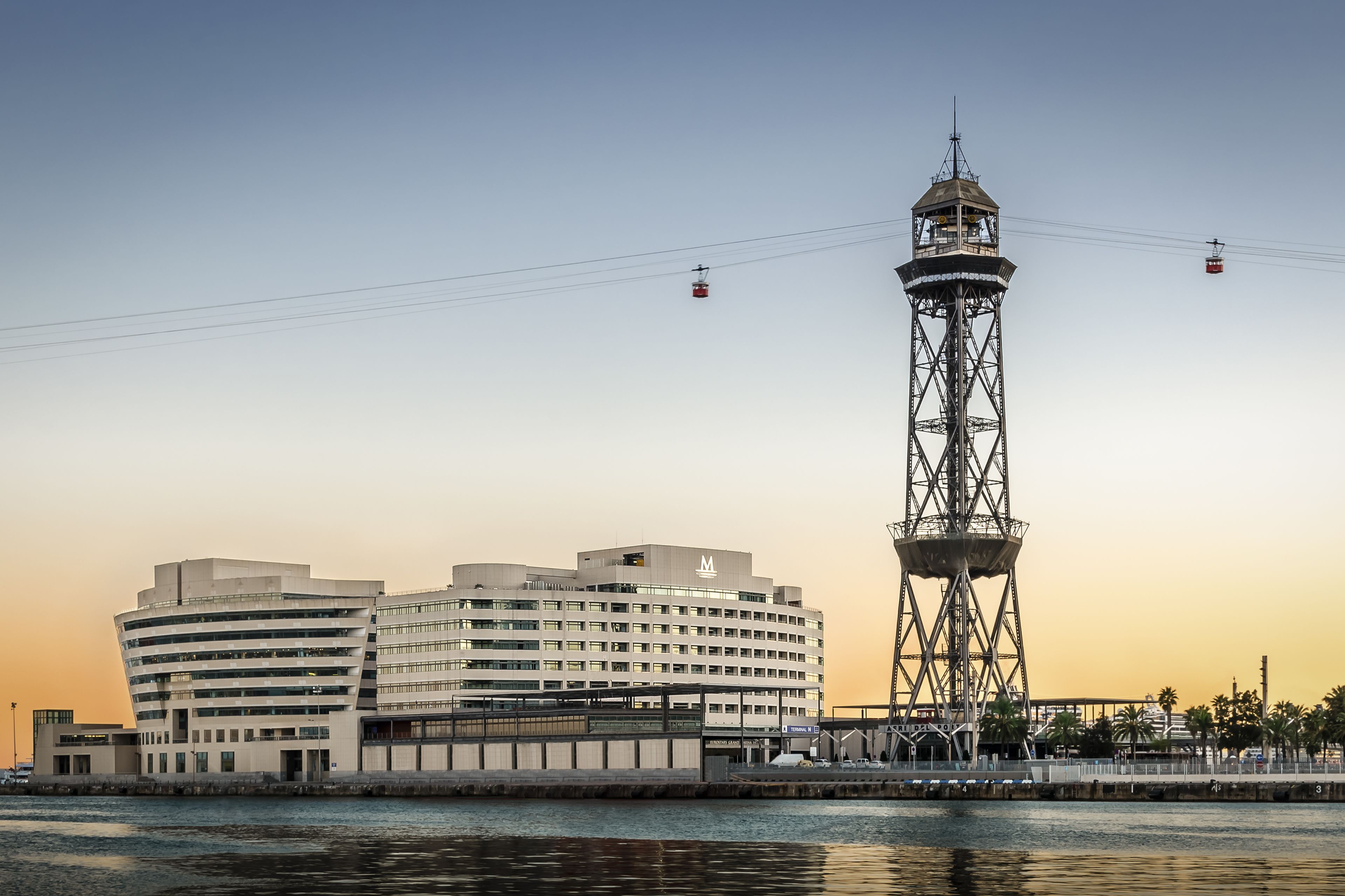 Un hotel moderno con fachada curva, una alta torre de observación y vistas al agua.