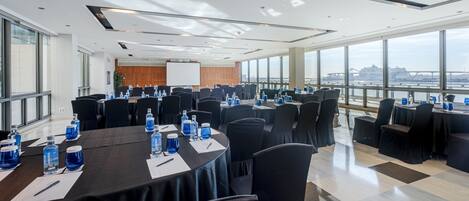 A conference room with tables set for meetings, large windows offering a view of a bridge, and a modern ceiling design.