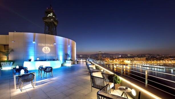 Un bar en la azotea con asientos y vistas al río al atardecer.
