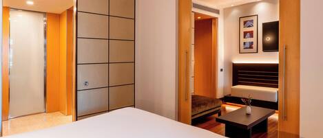 Habitación de hotel con una cama grande, zona de estar con mesa y armario con puertas correderas.