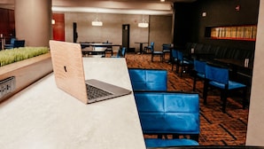 Un hall d’hôtel moderne comprenant un comptoir d’accueil, un espace salon et un bar.