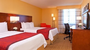 Une chambre d’hôtel avec deux lits, un bureau, une chaise et un téléviseur.
