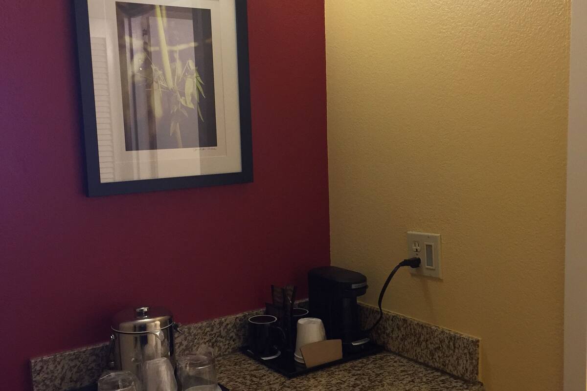 Eine Küche mit Granit Arbeitsplatten, einer Kaffeemaschine und einem gerahmten Bild an der Wand.