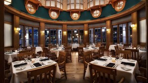 Un restaurante con mesas redondas, sillas de madera y amplios ventanales.