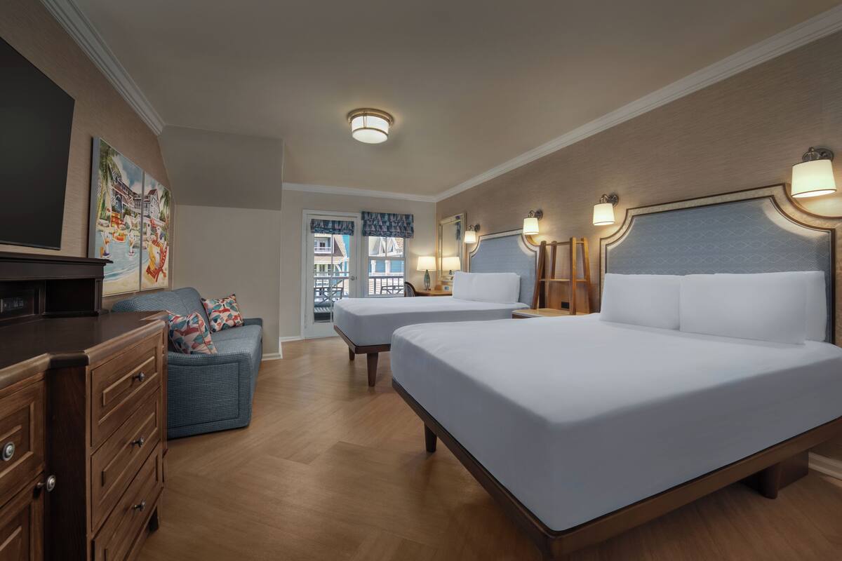 Ein Hotelzimmer mit zwei Betten, einem Schminktisch, einem Fernseher und Blick ins Freie.