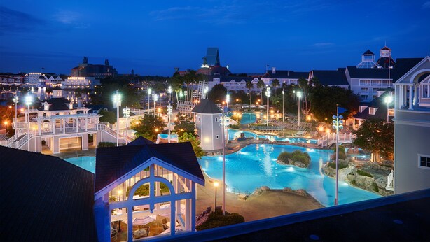 Un resort con una amplia piscina, varias edificaciones y un área exterior bien iluminada.