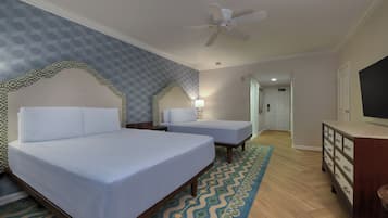 A hotel room with two beds, a ceiling fan, a dresser, and a TV.
