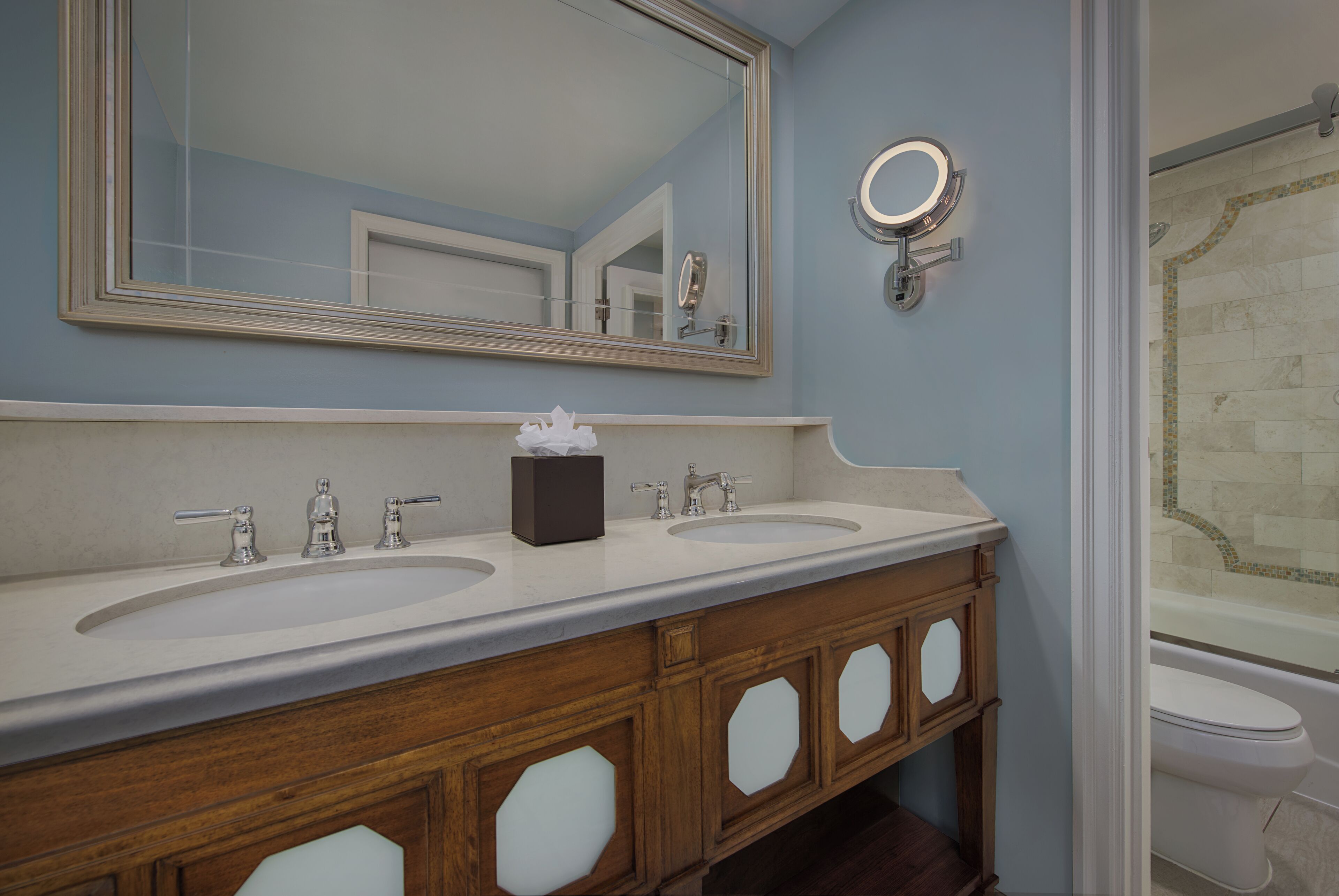 A bathroom with two sinks, a large mirror, and a round mirror above the sink.