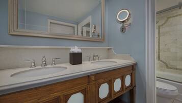 A bathroom with two sinks, a large mirror, and a round mirror above the sink.