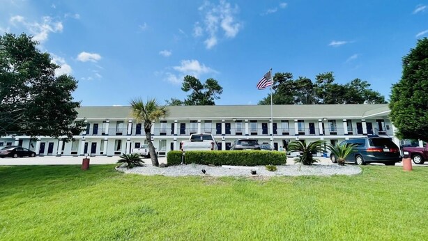 A motel with a row of rooms, a flag, and a well-maintained lawn. - Best Western Magnolia (GAUTIER (PASCAGOULA AREA))