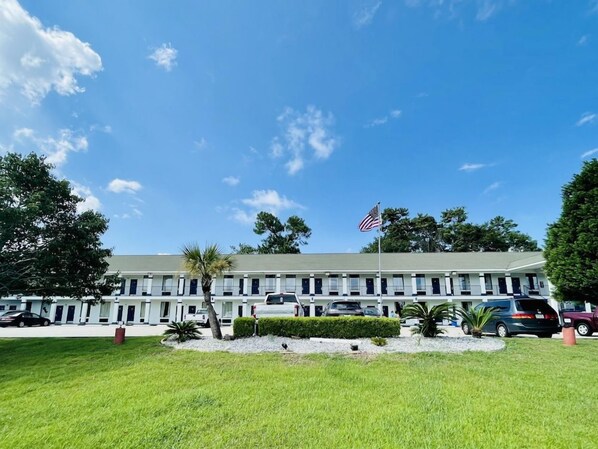 A motel with a row of rooms, a flag, and a well-maintained lawn. - Best Western Magnolia (GAUTIER (PASCAGOULA AREA))
