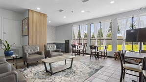 A spacious living area with a sofa, armchairs, a coffee table, and a dining table with chairs. - Best Western Magnolia (GAUTIER (PASCAGOULA AREA))