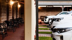 Un área de estar interior con mesas y sillas, una recepción y un estacionamiento con coches blancos.