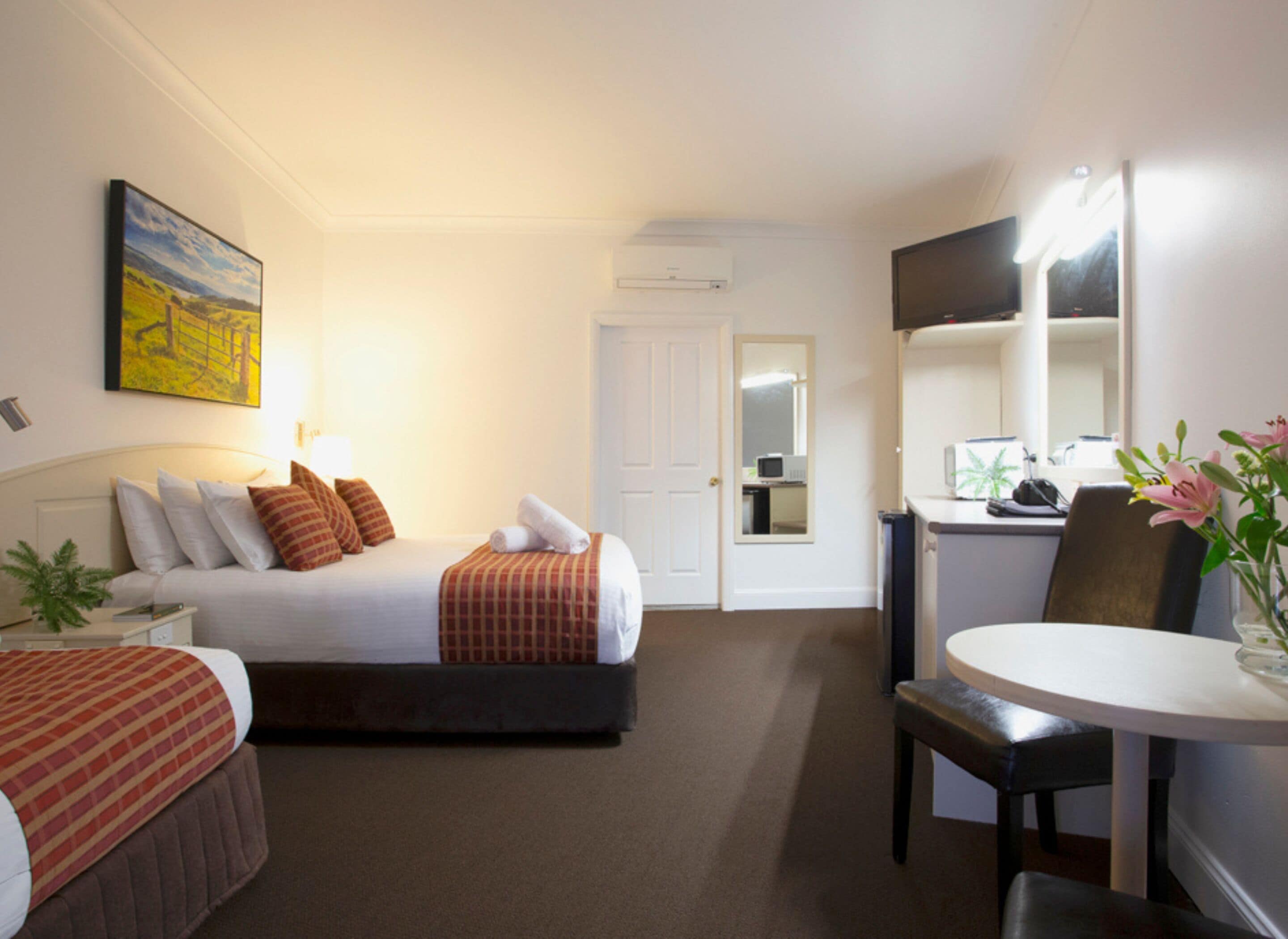 A hotel room with a bed, bedside table, lamp, and a desk with a chair.