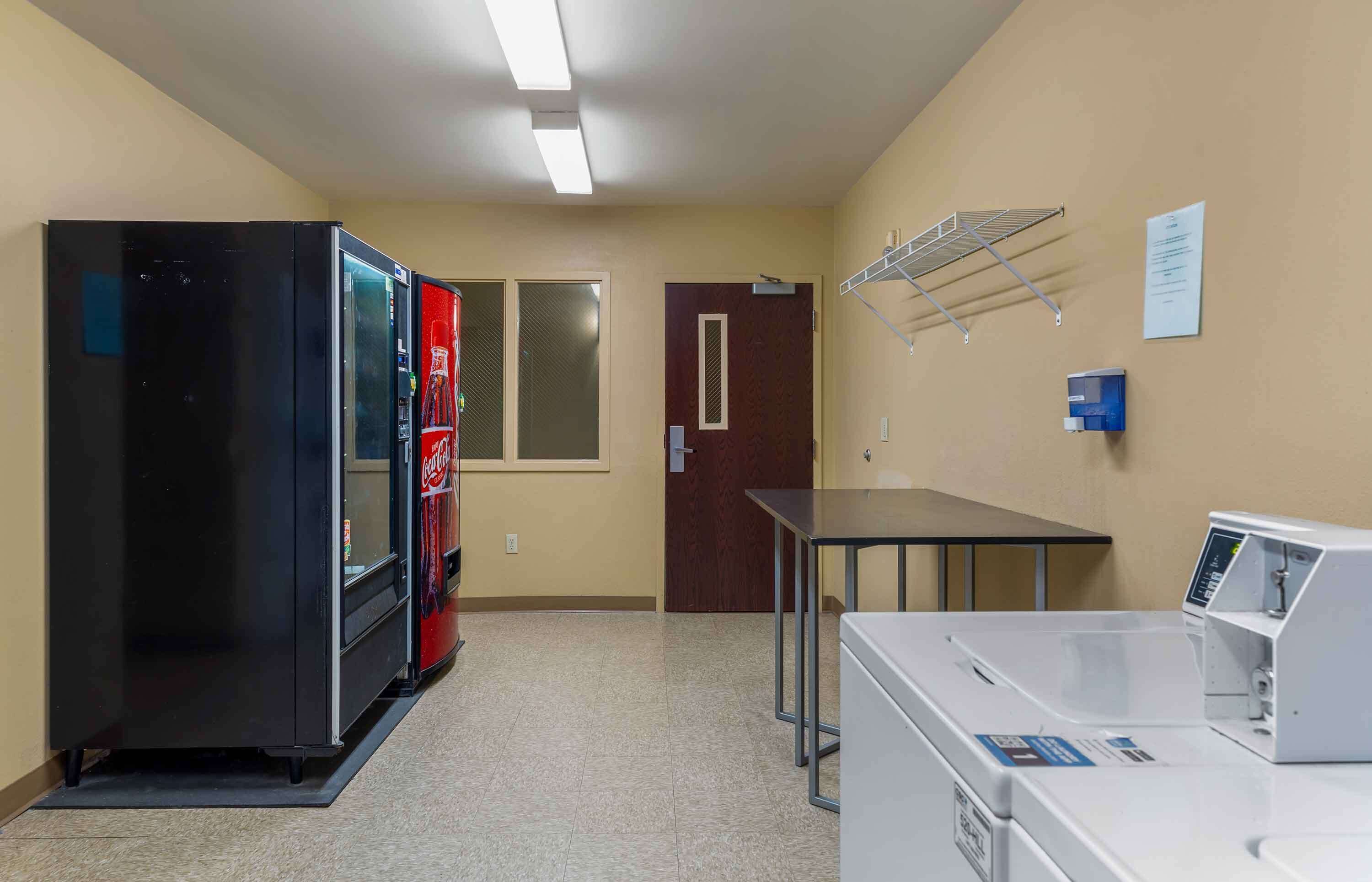 Una sala de lavandería con lavadora, secadora y refrigerador.